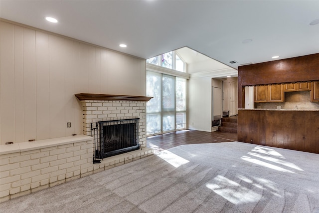 unfurnished living room featuring vaulted ceiling, a brick fireplace, and dark colored carpet