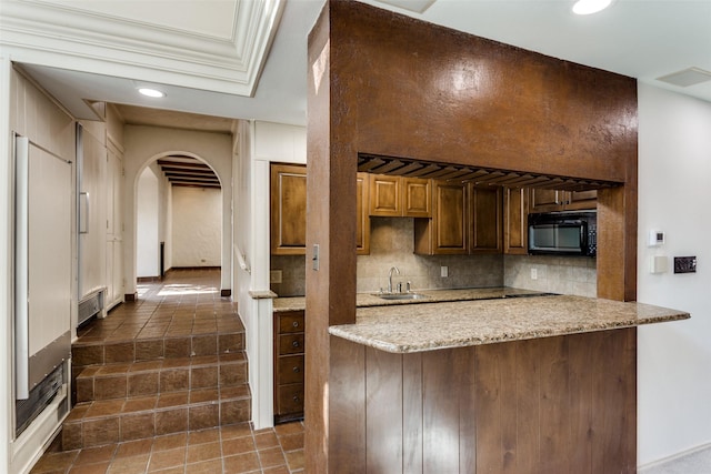 kitchen with sink, decorative backsplash, light stone countertops, and kitchen peninsula