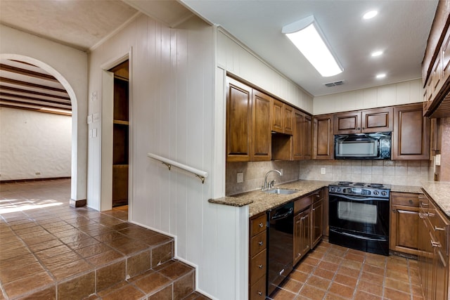 kitchen featuring backsplash, light stone countertops, sink, and black appliances