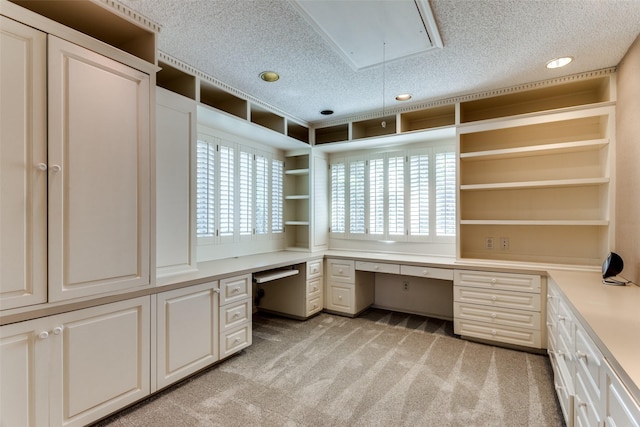 unfurnished office with light carpet, built in desk, and a textured ceiling