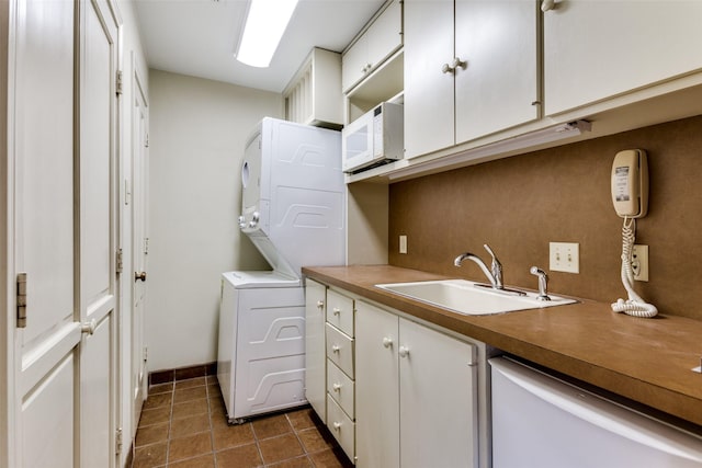 laundry room with sink, cabinets, dark tile patterned floors, and stacked washing maching and dryer