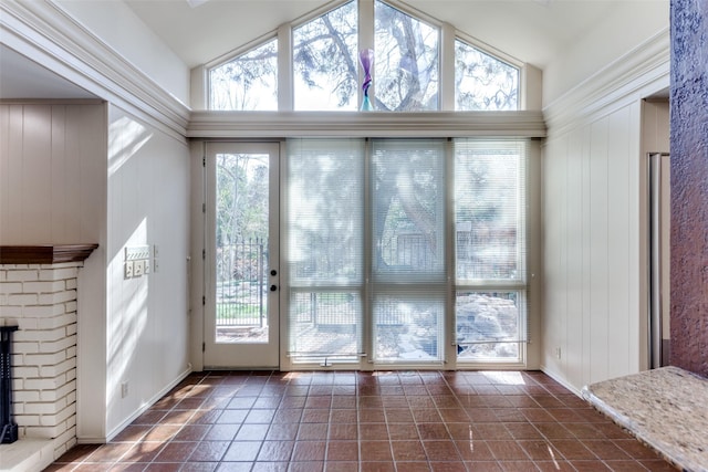 doorway to outside featuring lofted ceiling, dark tile patterned flooring, and a fireplace