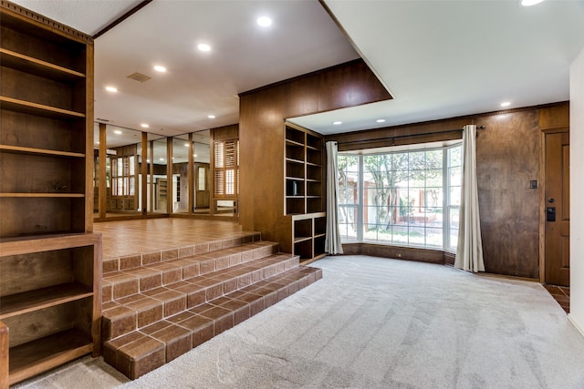 interior space with built in features, wooden walls, and light carpet