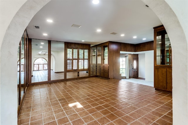 unfurnished living room featuring wood walls