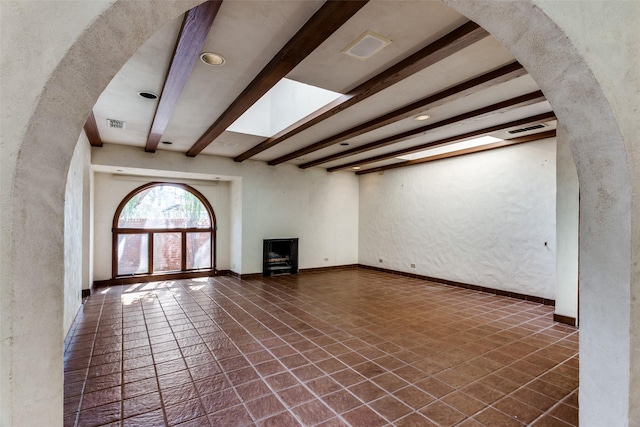 unfurnished living room featuring a skylight and beamed ceiling