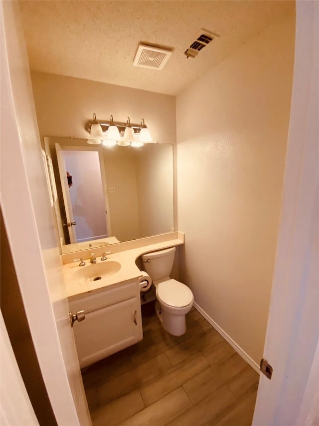 bathroom featuring vanity, hardwood / wood-style floors, a textured ceiling, and toilet