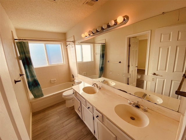 full bathroom with shower / tub combo with curtain, hardwood / wood-style flooring, vanity, toilet, and a textured ceiling