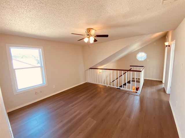 additional living space with ceiling fan, dark wood-type flooring, and a textured ceiling