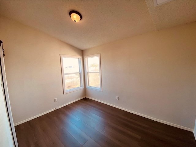 unfurnished room with vaulted ceiling, dark hardwood / wood-style floors, and a textured ceiling