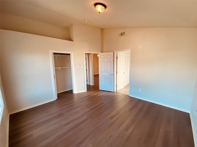 unfurnished bedroom featuring dark wood-type flooring, vaulted ceiling, and a closet