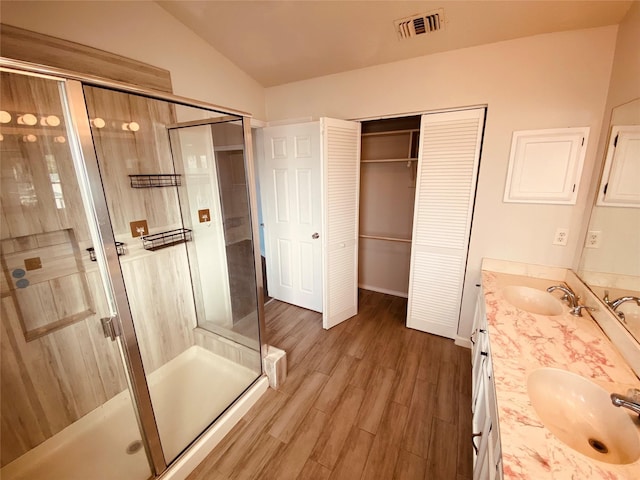 bathroom with vanity, hardwood / wood-style floors, a shower with shower door, and lofted ceiling