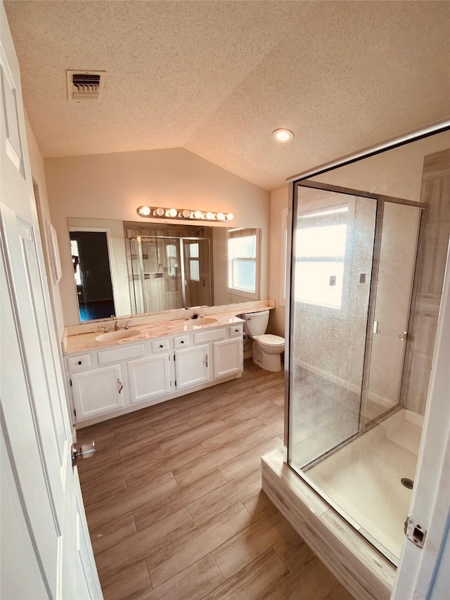 bathroom featuring lofted ceiling, a shower with door, hardwood / wood-style floors, vanity, and toilet