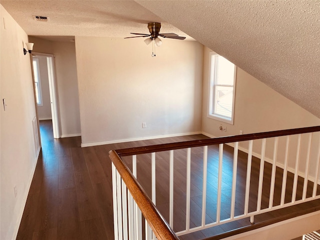 interior space with lofted ceiling, ceiling fan, dark hardwood / wood-style floors, and a textured ceiling