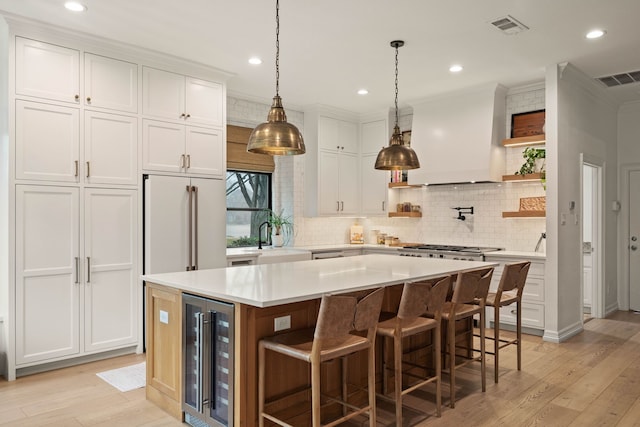 kitchen with a kitchen island, white cabinets, wine cooler, light hardwood / wood-style floors, and custom range hood