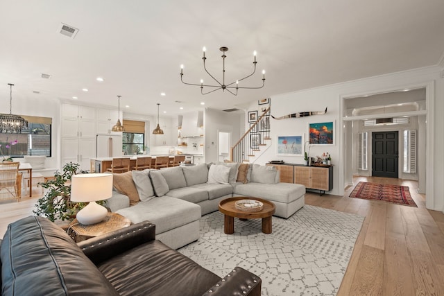 living room featuring crown molding, an inviting chandelier, and light hardwood / wood-style floors