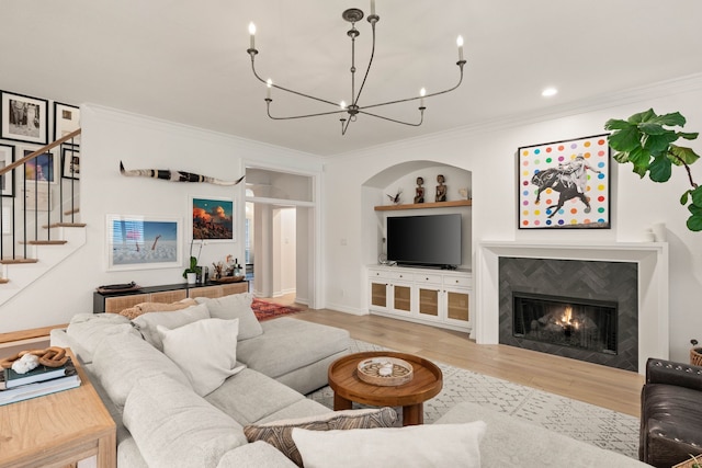 living room featuring an inviting chandelier, ornamental molding, built in features, and light wood-type flooring