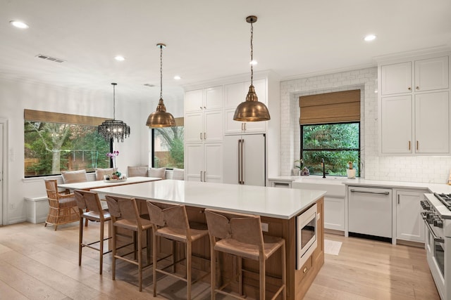 kitchen with high end appliances, a kitchen island, sink, and white cabinets