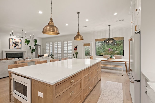 kitchen with white refrigerator, pendant lighting, a large island, and stainless steel microwave