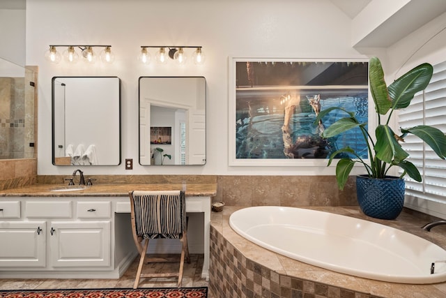 bathroom featuring tiled tub and vanity