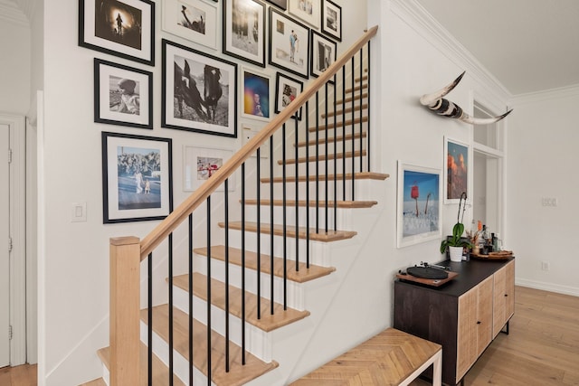 stairway with ornamental molding and hardwood / wood-style floors