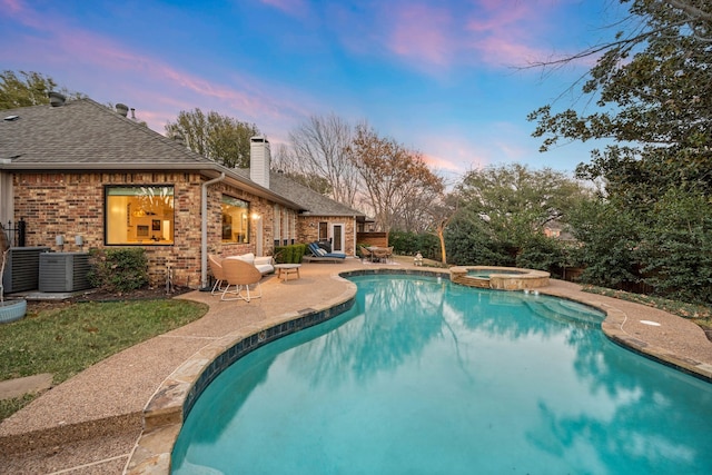 pool at dusk with a patio area, central air condition unit, and an in ground hot tub