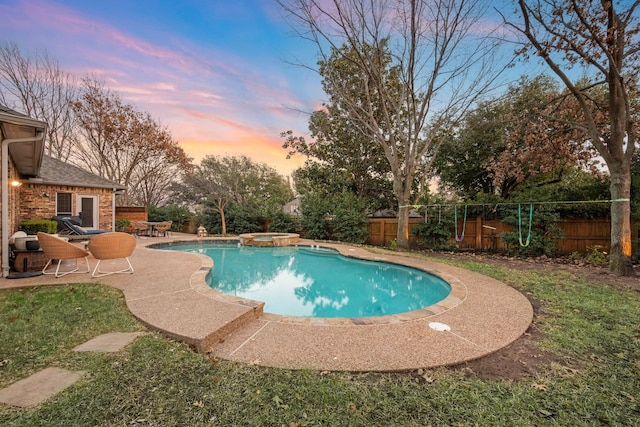 pool at dusk featuring an in ground hot tub and a patio area