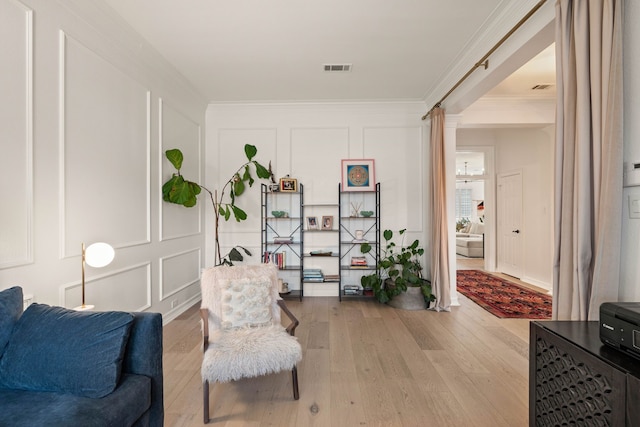 sitting room with crown molding and light hardwood / wood-style flooring