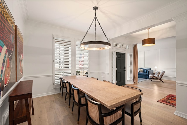 dining area with ornamental molding and light hardwood / wood-style flooring