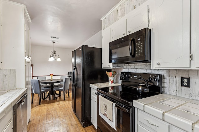 kitchen featuring tile countertops, visible vents, white cabinetry, black appliances, and tasteful backsplash