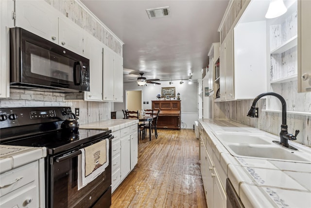 kitchen featuring tile countertops, a sink, visible vents, white cabinets, and black appliances