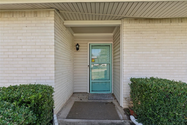 view of exterior entry featuring brick siding