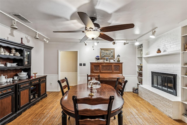 dining area with visible vents, built in features, wainscoting, light wood-type flooring, and a fireplace