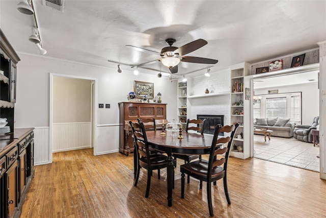 dining area featuring visible vents, built in features, wainscoting, light wood-type flooring, and a fireplace