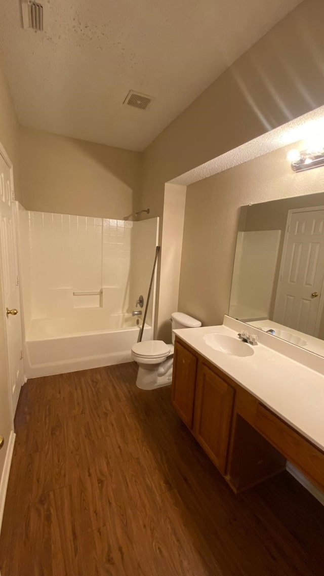 bathroom with toilet, tub / shower combination, wood finished floors, and visible vents