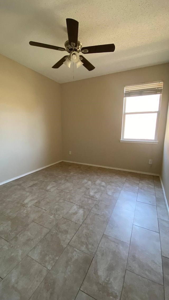 spare room featuring a textured ceiling and baseboards