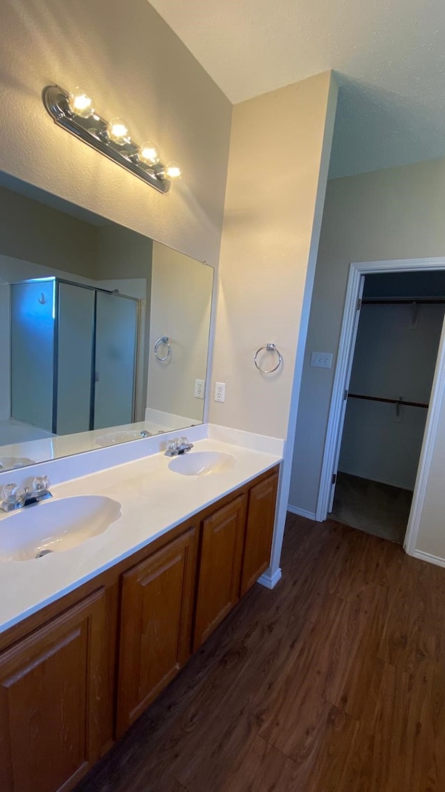 bathroom with double vanity, a sink, and wood finished floors