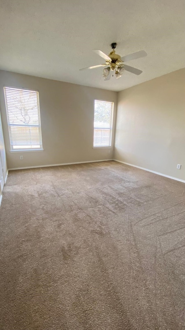 carpeted empty room featuring ceiling fan, a textured ceiling, and baseboards