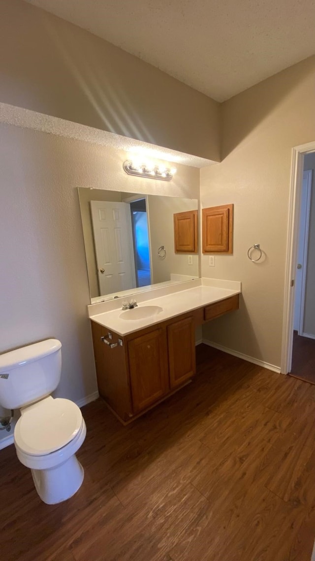 bathroom with vanity, wood finished floors, toilet, and baseboards