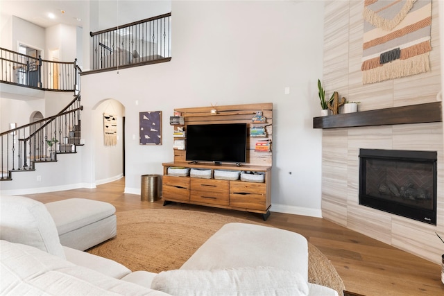 living room with a towering ceiling, a fireplace, and hardwood / wood-style floors