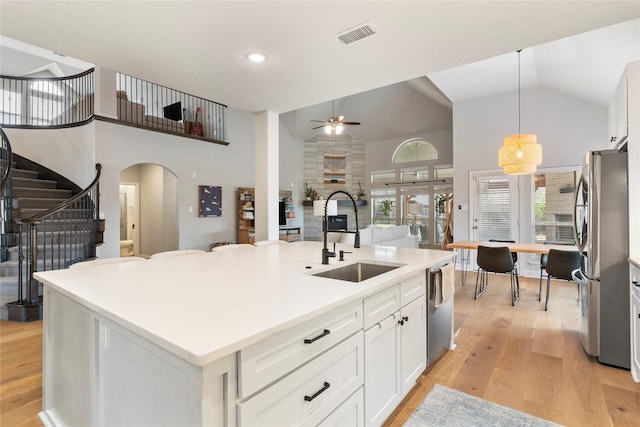 kitchen featuring sink, appliances with stainless steel finishes, a kitchen island with sink, white cabinetry, and decorative light fixtures