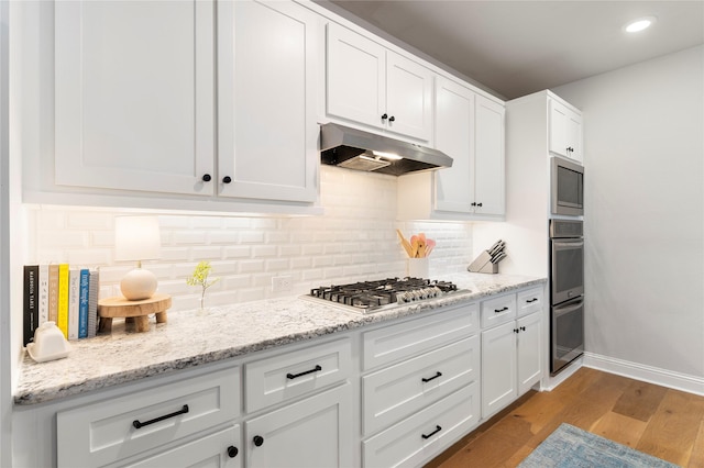 kitchen featuring backsplash, stainless steel appliances, light hardwood / wood-style flooring, and white cabinets