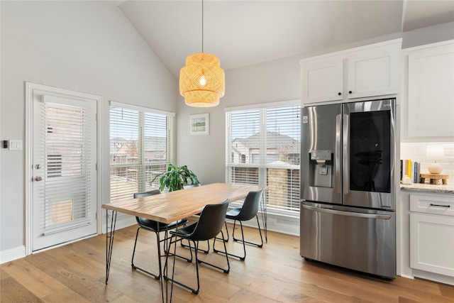 dining area with vaulted ceiling and light hardwood / wood-style floors