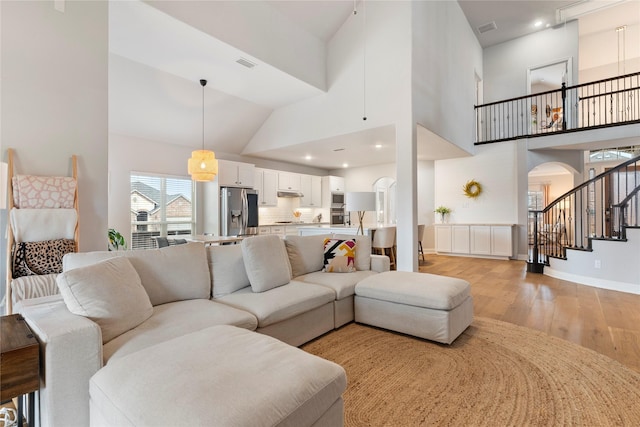 living room featuring high vaulted ceiling and light hardwood / wood-style flooring