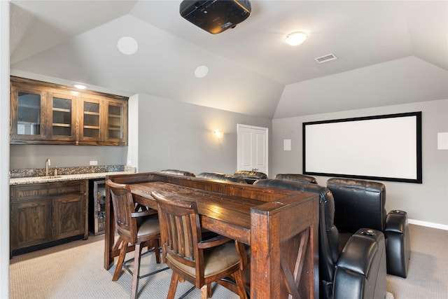 carpeted cinema room featuring wine cooler, wet bar, and vaulted ceiling