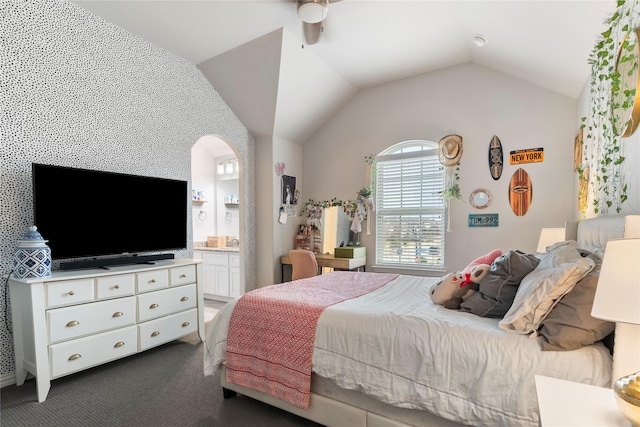 bedroom featuring ensuite bath, dark carpet, and vaulted ceiling