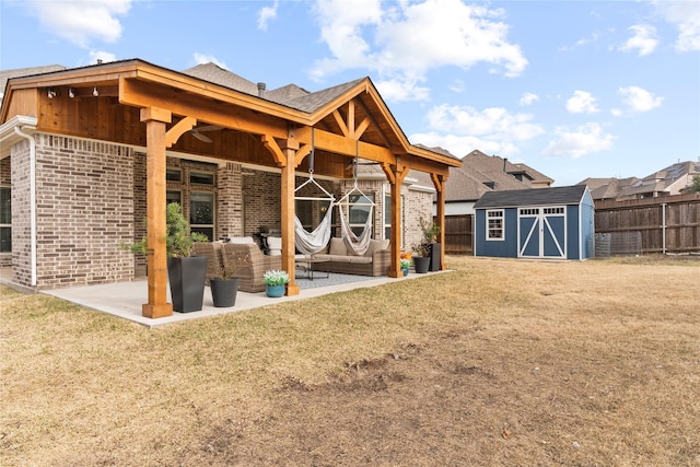 back of house featuring an outbuilding, brick siding, a patio, a storage shed, and fence