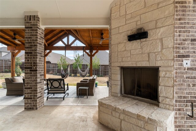 view of patio / terrace featuring ceiling fan, a gazebo, an outdoor stone fireplace, and a fenced backyard