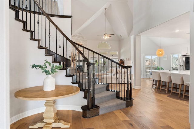 stairs featuring baseboards, high vaulted ceiling, and wood finished floors