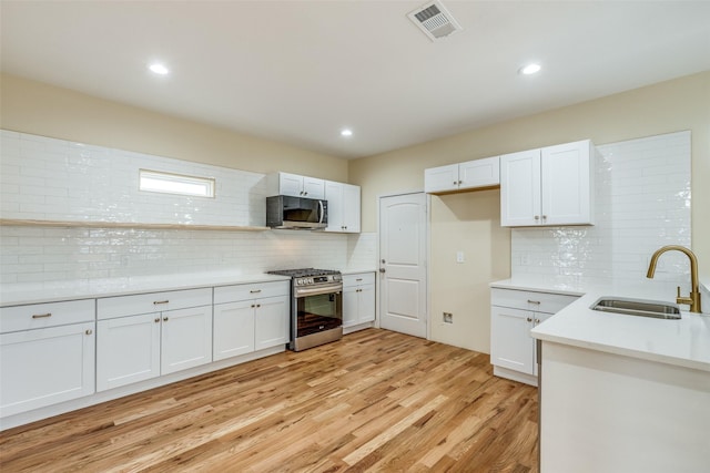 kitchen with white cabinetry, appliances with stainless steel finishes, sink, and light hardwood / wood-style flooring