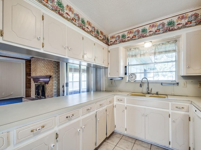 kitchen with light tile patterned flooring, sink, a textured ceiling, kitchen peninsula, and white cabinets